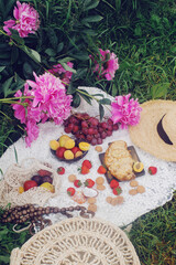 Outdoor summer picnic in french style with fresh organic fruits, peony flowers, almond croissant