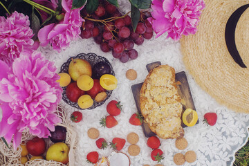 Outdoor summer picnic in french style with fresh organic fruits, peony flowers, almond croissant