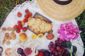 Outdoor summer picnic in french style with fresh organic fruits, peony flowers, almond croissant