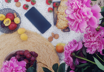 Outdoor summer picnic in french style with fresh organic fruits, peony flowers, almond croissant