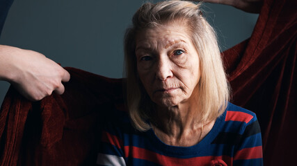 Young person covering his grandmother with red blanket. Care of elderly people in nursing home. High quality photo