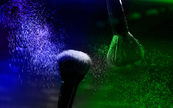 explosion of green and blue eyeshadows on dark background. makeup brushes. High quality photo