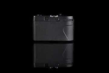 The old 35mm. scaling film camera on black glass background with reflection.
