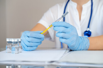 Fototapeta premium Nurse holds syringe with antiviral vaccine during vaccination campaign. Immunization and disease prevention concept. Selective focused. Close up. Unrecognized personality