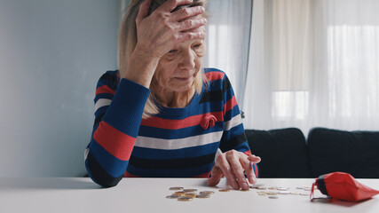Poor old woman counting coins on the table. Hopeless elderly lady with financial problems. High quality photo
