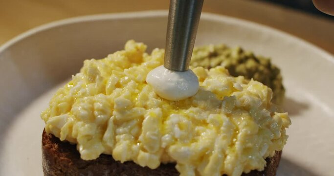 The chef uses a chef's siphon to add a delicate Parmesan mousse on top of the scramble eggs toast