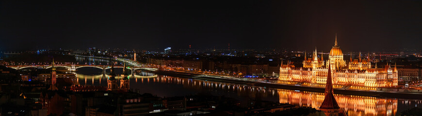 Fototapeta na wymiar Night Budapest, Parliament against the background of the night city, reflection of lights in the river, panorama of the city
