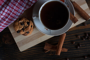 A cup of aromatic black coffee, grains of different varieties on the table and cinnamon sticks. Morning espresso or Americano coffee for breakfast in a beautiful cup. Still life. View from above. 