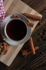 A cup of aromatic black coffee, grains of different varieties on the table and cinnamon sticks. Morning espresso or Americano coffee for breakfast in a beautiful cup. Still life. View from above. 