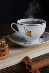 A cup of aromatic black coffee, grains of different varieties on the table and cinnamon sticks and chocolate chip cookies. Morning espresso or Americano coffee for breakfast in a beautiful cup. 