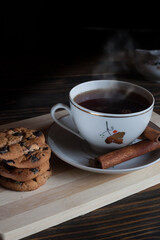 A cup of aromatic black coffee, grains of different varieties on the table and cinnamon sticks and chocolate chip cookies. Morning espresso or Americano coffee for breakfast in a beautiful cup. 