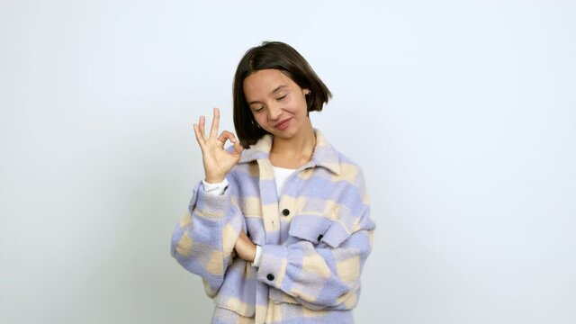 Young latin woman showing ok sign with fingers over isolated background