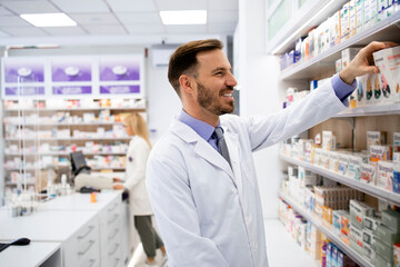 Pharmacist working in pharmacy store and arranging boxes of medicines on the shelf.