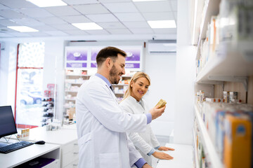 Obraz premium Pharmacists working in pharmacy store and arranging medicines on the shelf.
