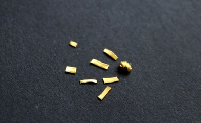 An expensive grain of pure gold 24 karat with golden chips around it in the form of falling star or...