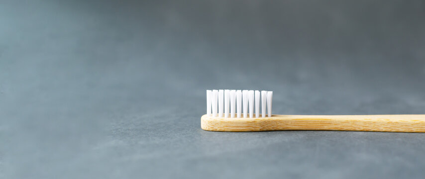 One bamboo toothbrush lies on a black background. Eco friendly stuff concept. Copy space. Horizontal orientation. Baner.
