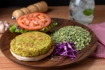 Homemade vegan and vegetarian hamburgers of legumes and vegetables with potatoes lettuce tomato on wooden plate for a healthy diet and life