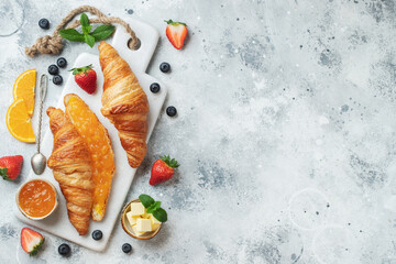 Fresh sweet croissants with butter and orange jam for breakfast. Continental breakfast on a white concrete table. Top view with copy space. Flat lay