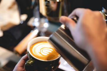 professional barista making latte art from coffee and milk, hand holding a cup of latte, espresso, cappuccino, drink in the morning breakfast