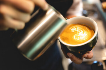 professional barista making latte art from coffee and milk, hand holding a cup of latte, espresso, cappuccino, drink in the morning breakfast