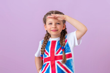 A little girl with pigtails and an image of the English flag looks into the distance.