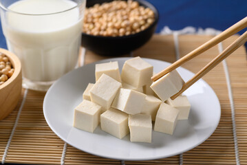 Sliced tofu on white dish eating by chopsticks, Healthy vegan food