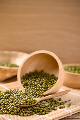 Pile of mung bean seeds in a wooden spoon and bowl, Food ingredients in Asian cuisine and produce mung bean sprout