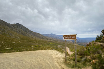 Scenic view and Skelmdraai (sly corner) sign with bullet holes at Swartberg Pass (black mountain pass), South Africa