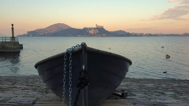 Fishing boat out of water and tied with iron chain facing Lake Maggiore and Angera castle, static