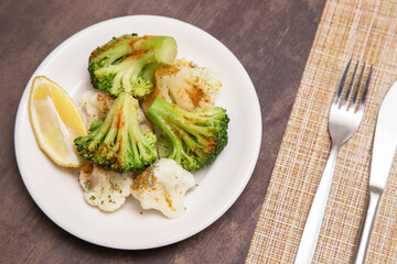 Broccoli and cauliflower with spices and lemon on white plate. Vegan vegetarian healthy diet food concept