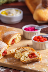 Fatias de pão recheado com calabresa acompanhadas de pastas de tomate, beterraba e iogurte.