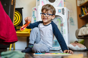 Portrait of happy caucasian boy with eyeglasses sitting at home in room in day real people small...