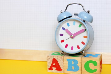 English alphabet. ABC letters on wooden toy blocks. Color funny alarm clock.