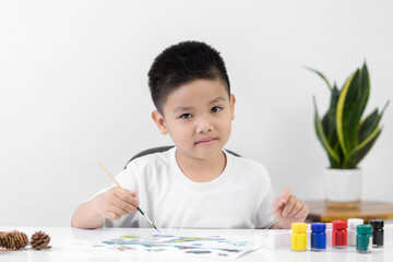 Happy little Asian kid at the table draw with water color Learning and education of kid.