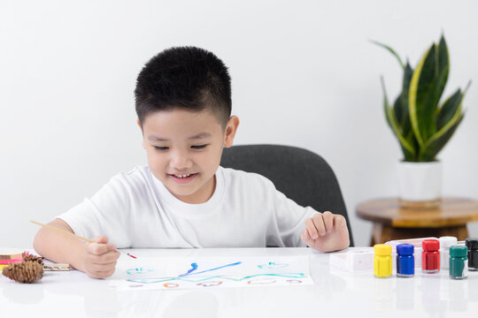 Happy little Asian kid at the table draw with water color Learning and education of kid.