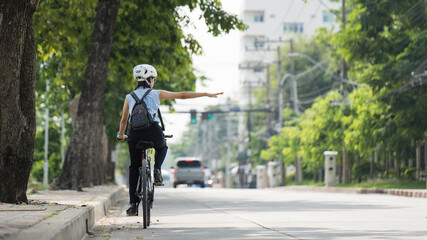 Workers women go cycling in the city to work at rush hour.She gave her arm to the traffic signal.