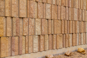 Modern style rough textured limestone brick wall background with attractive vertical aligned natural kasota stone blocks in varying widths and shades of light brown with foundation rock decoration.