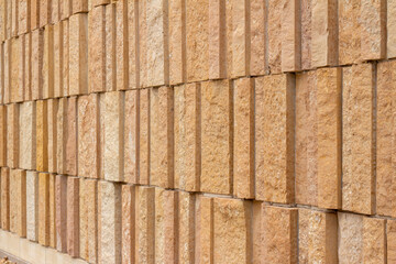 This image shows a modern style rough textured limestone brick wall background with attractive vertical aligned natural kasota stone blocks in varying widths and shades of light brown.