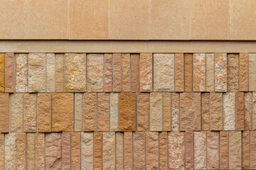 This image shows a modern style rough textured limestone brick wall background with attractive vertical aligned natural kasota stone blocks in varying widths and shades of light brown.