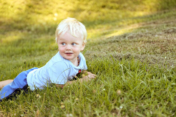 Little boy lying on grass at the park smiling off into the distance at sunset