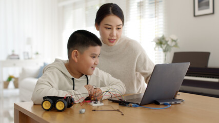 Young asia student remotely learn online at home with parent in coding robot car and electronic...
