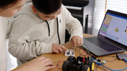 Young asia student remotely learn online at home with parent in coding robot car and electronic board cable in STEM, STEAM, mathematics engineer science technology computer code in robotics for kids.