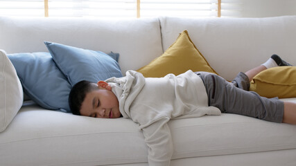 Fatigue in children laying fall down asleep slumber on sofa at home need rest or brain break after virtual study online remote learn at home problem in asian kid feel lack of energy and tired.