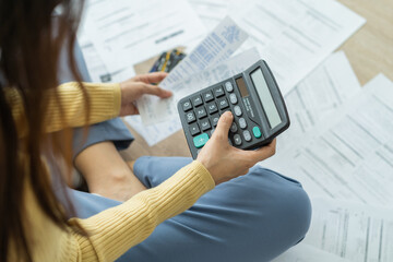 Top view owe asian woman, female sitting on floor stressed and confused by calculate expense from invoice or bill, have no money to pay, mortgage or loan. Debt, bankruptcy or bankrupt concept.