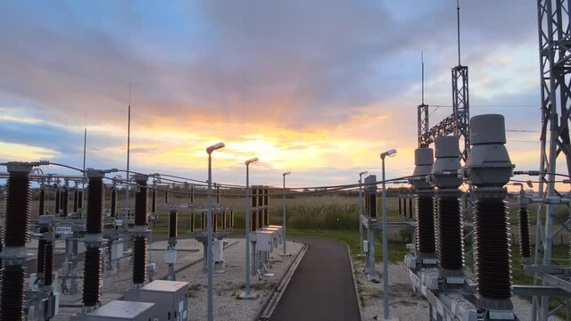 Aerial view of sunset at a High voltage power station - rising, tilt drone shot