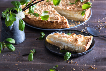 Beautiful and tasty curd pie on a wooden background surrounded by greenery. Spring breakfast, herbs, morning, homemade cakes. Selective focus.