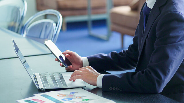 パソコンをしながらスマホを見るビジネスマン