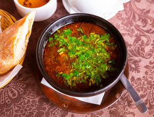Hearty rich kharcho soup with lamb garnished with fresh greens. Traditional dish of Georgian cuisine..