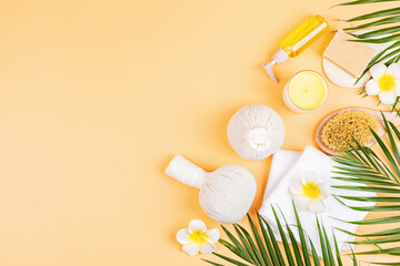 Spa massage Aromatherapy body care background. Spa herbal balls, cosmetics, towel and tropical leaves on orange table. Top view, flat lay, overhead, copy space. Beauty and health care concept