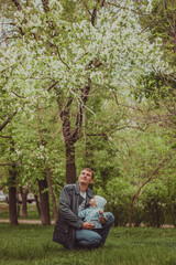 Fototapeta premium Small cute baby boy with his father walking in spring park outdoor. Blooming trees in the garden. Smile and parent care